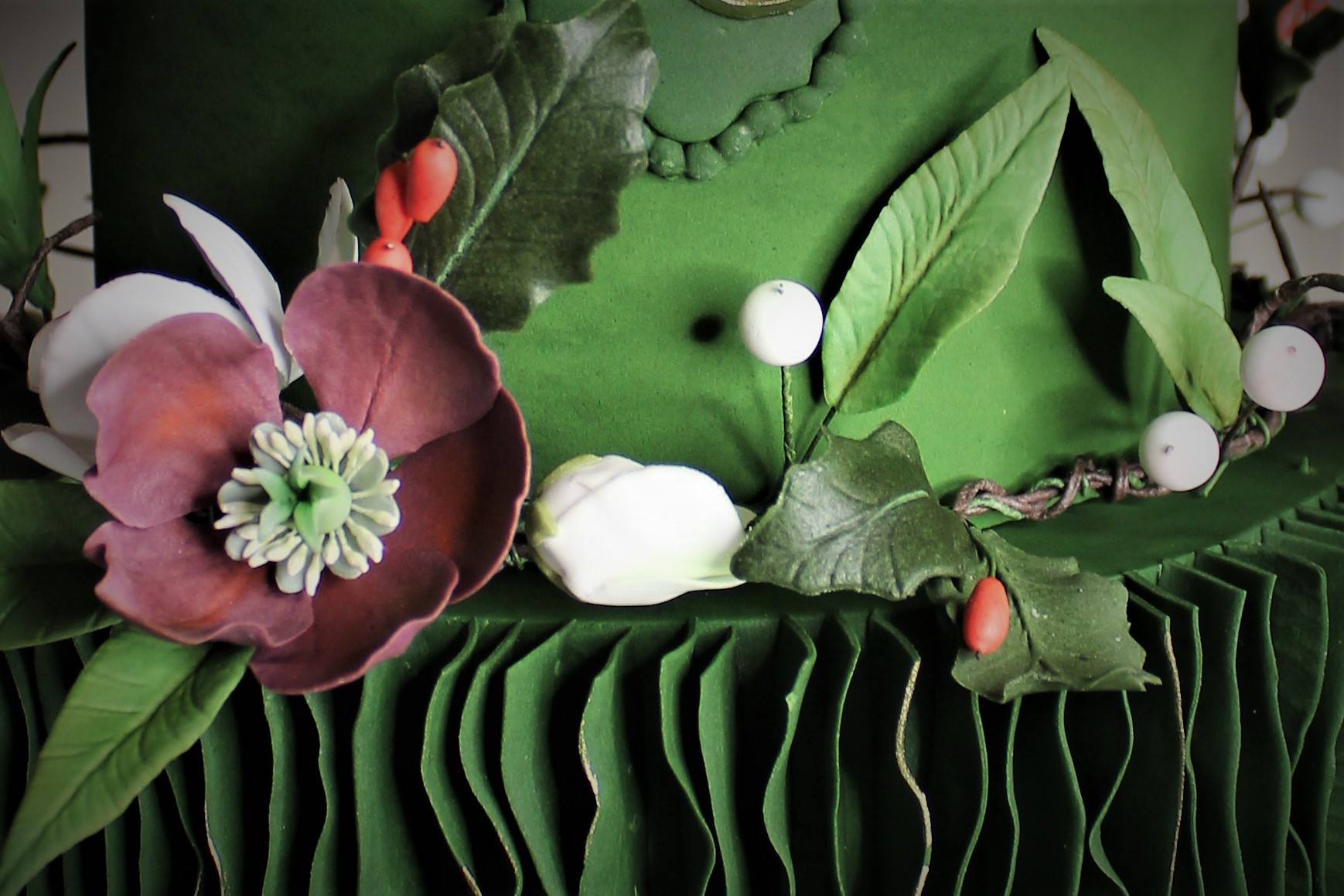 Close-up of fondant flowers and holly leaves