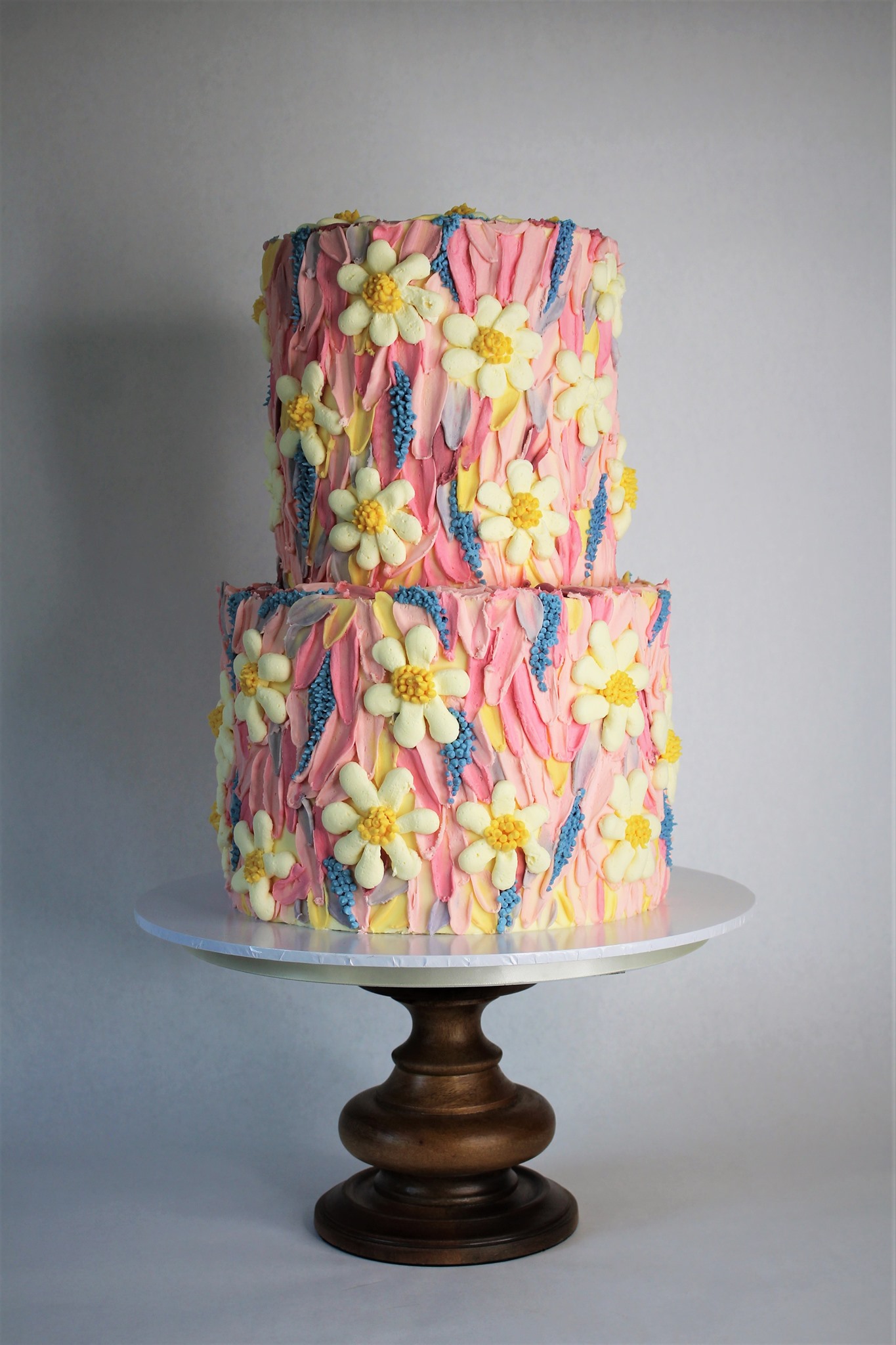 A two tier Wedding Cake with fondant flowers adorned on the outside