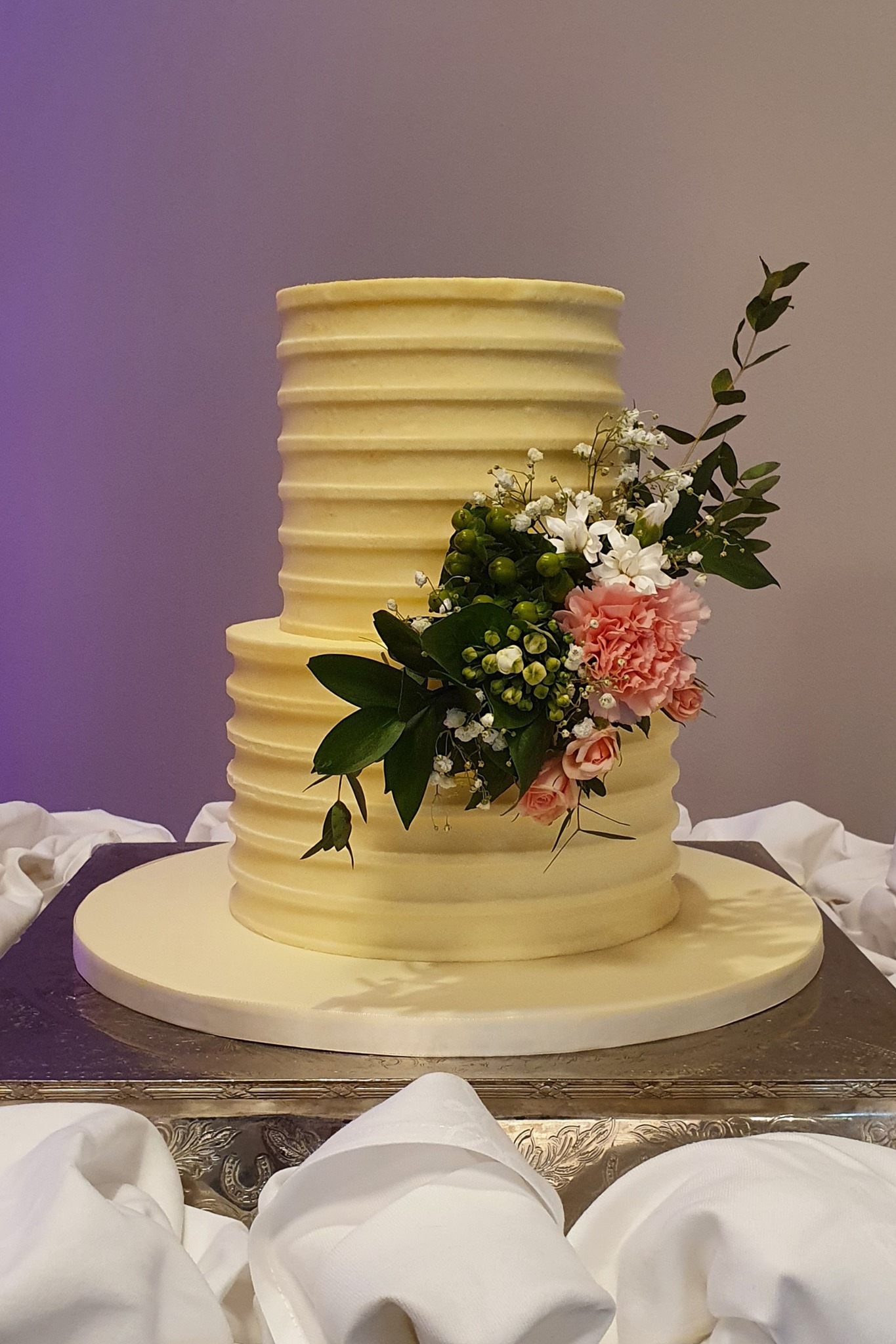 Two tiered cream coloured wedding cake with a flower bouquet