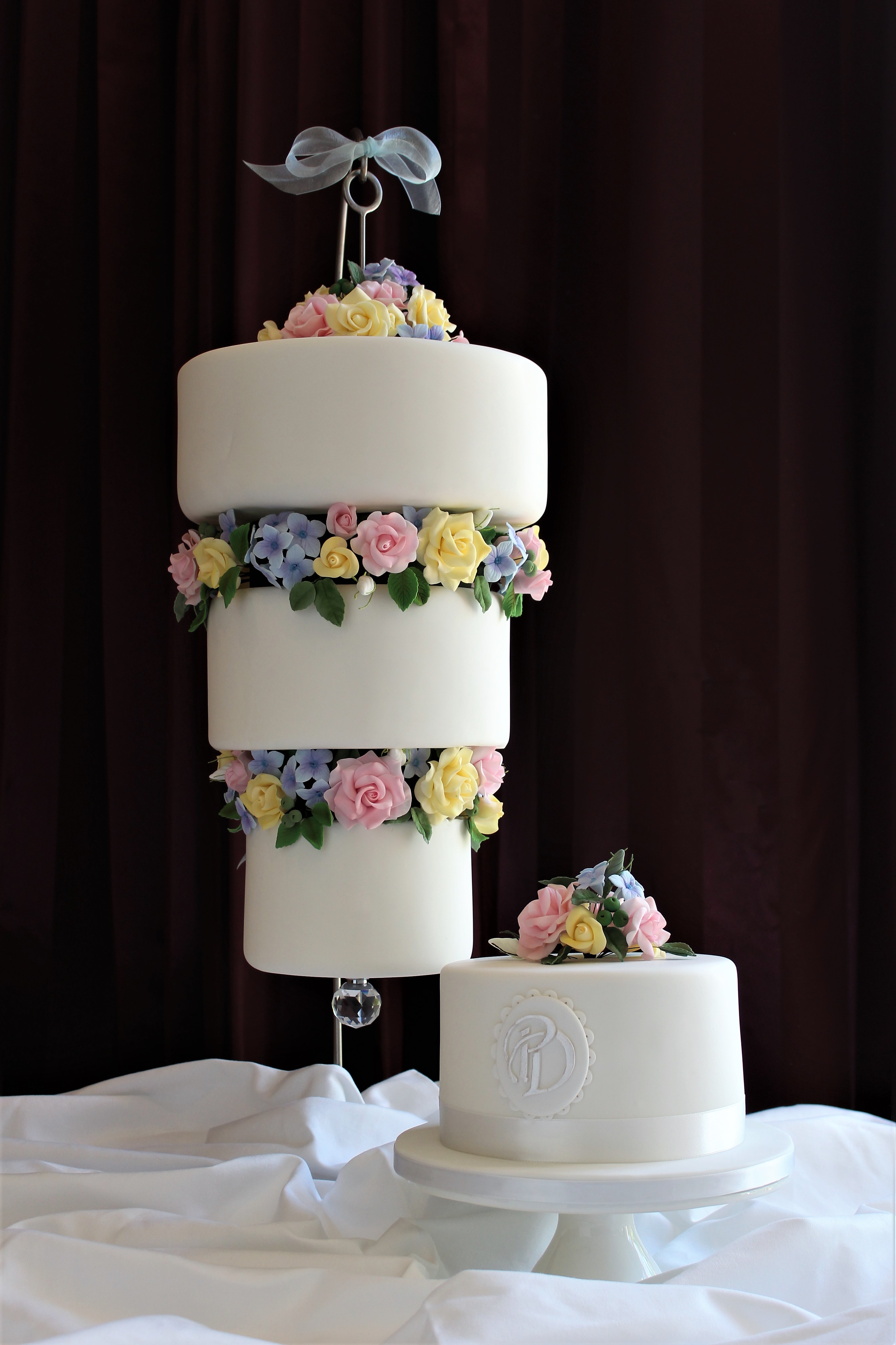 A suspended, up-side-down, three-tier wedding cake accompanied by a monogrammed Red
                                    Velvet Cake to cut for the traditional 'cutting' photograph.