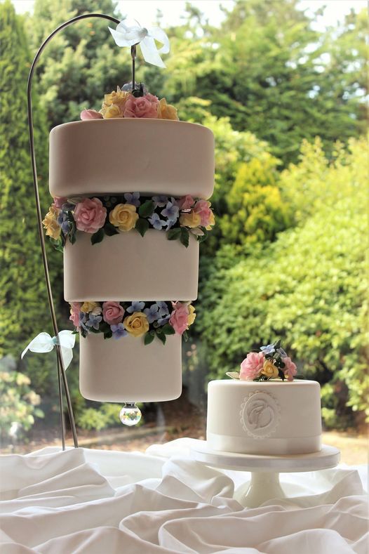 A suspended, up-side-down, three-tier wedding cake accompanied by a monogrammed Red
                    Velvet Cake to cut for the traditional 'cutting' photograph.